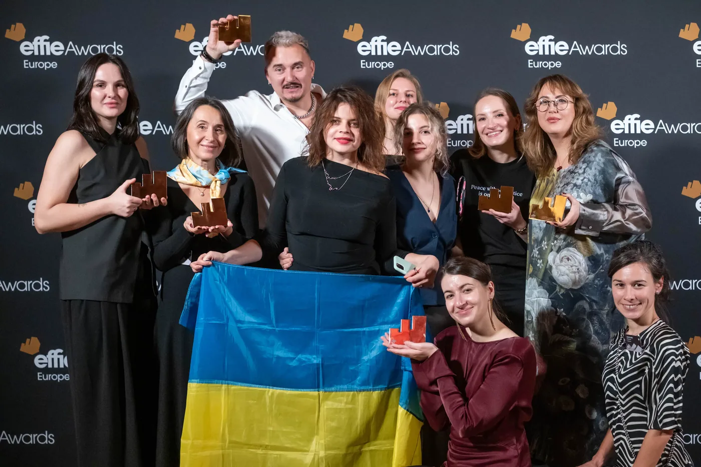 A large group holding a Ukrainian flag and trophies at the Effie Awards Europe